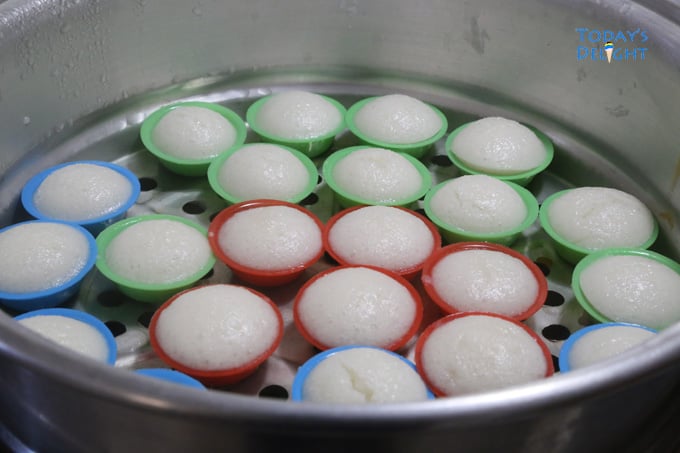 Whiite puto calasiao (rice cakes) in molds on a steamer.