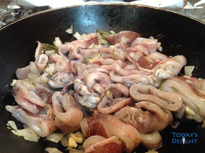 Adobong pusit recipe is a Filipino dish in a pan with cut squid with head and tentacles in vinegar.