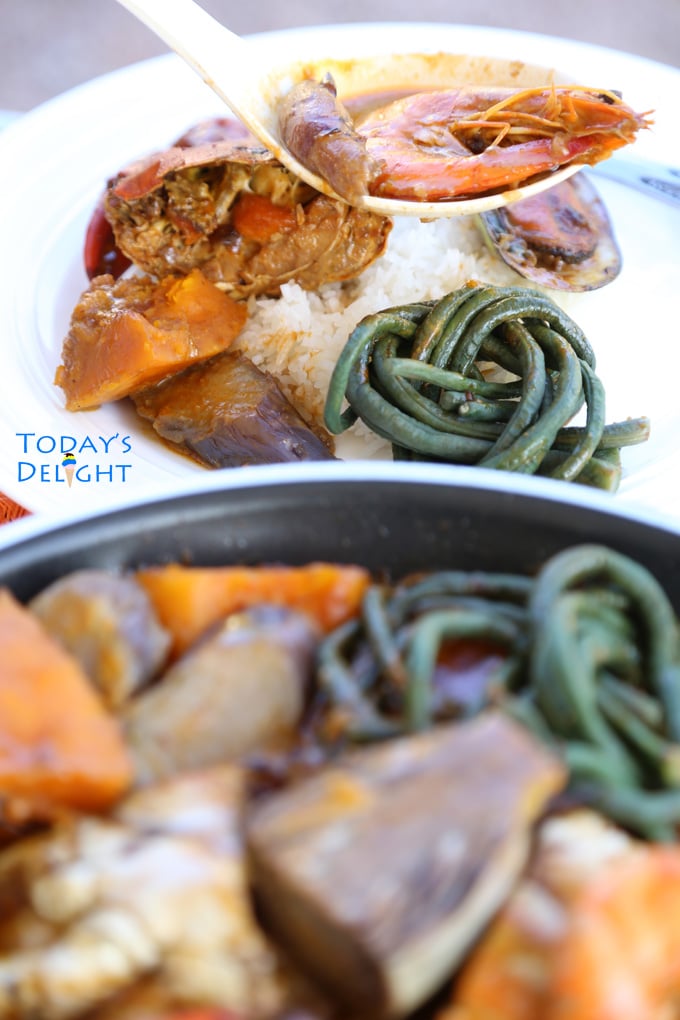 Seafood kare kare in a skillet and served over rice.