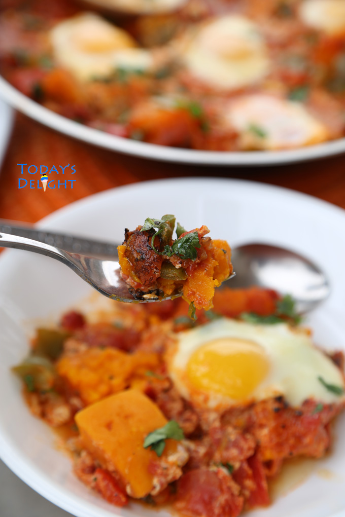 A plate of shakshuka with poached egg and kabocha squash on a fork.