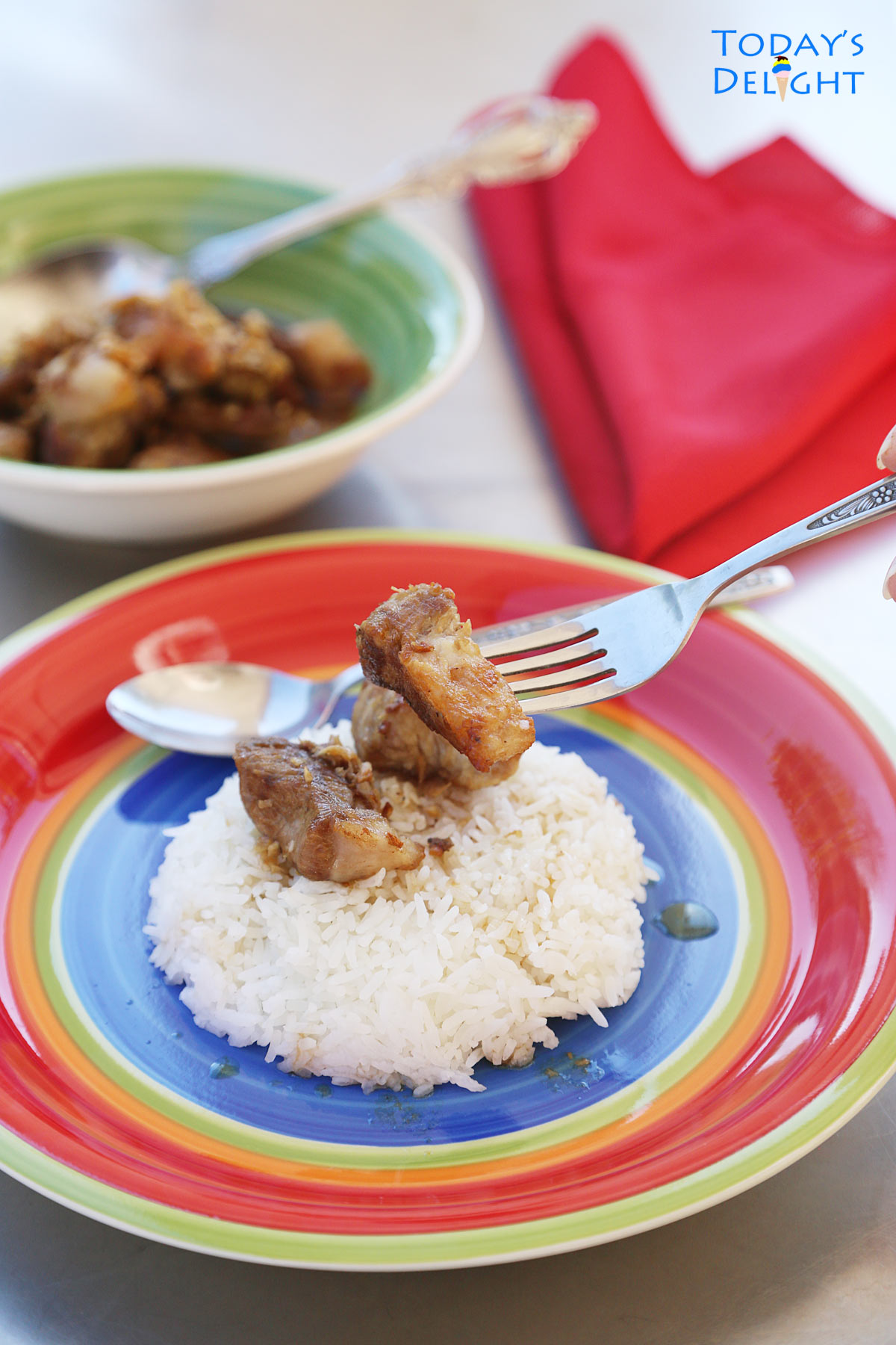 Pork adobo and sauce over white rice and a serving of dish in a bowl.