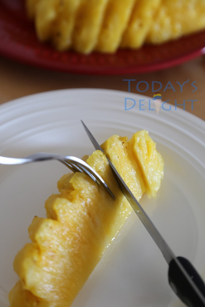 A fork holding a pineapple while sliced into bite-size on a plate. A red plate full of sliced pineapples.
