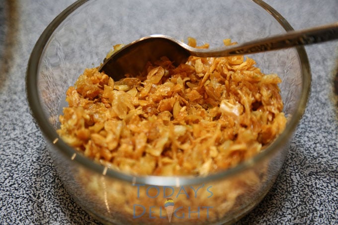Toasted garlic in a glass cup with a spoon.