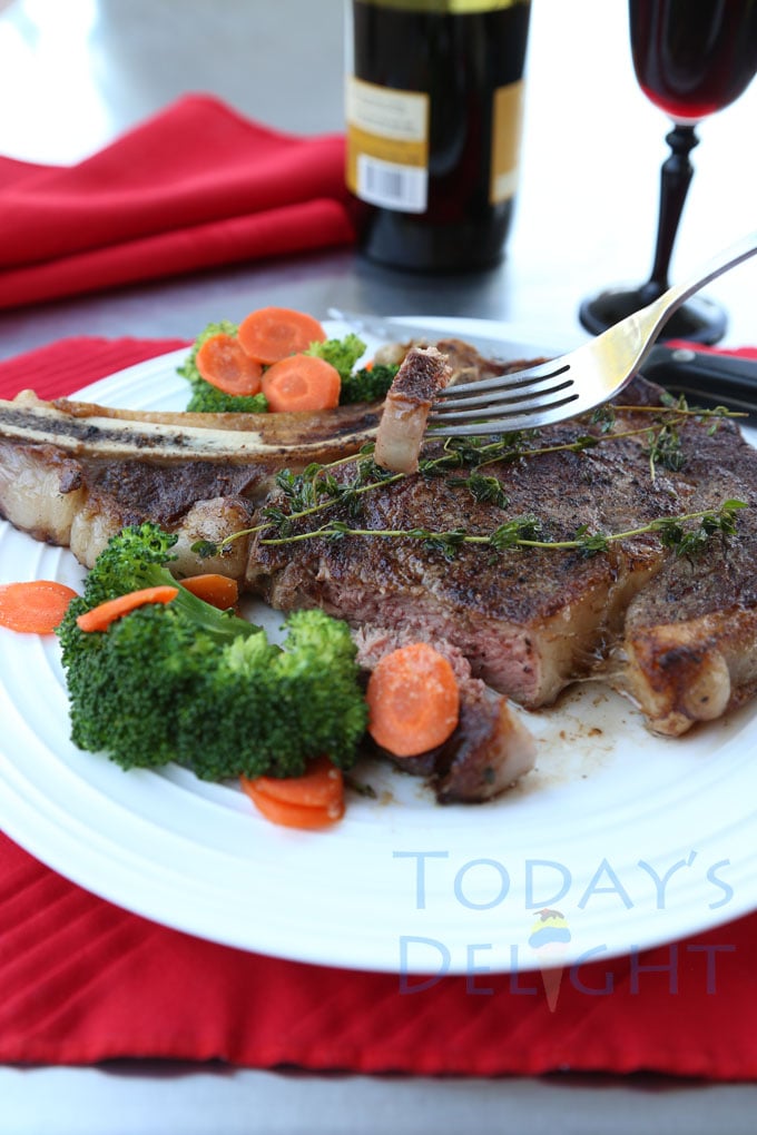 Steak on a plate with carrots and broccoli and slice of steak on a fork.