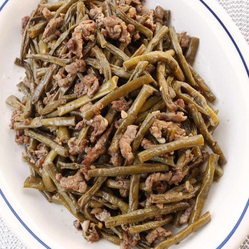 Cooked cut string beans with pork in a platter.