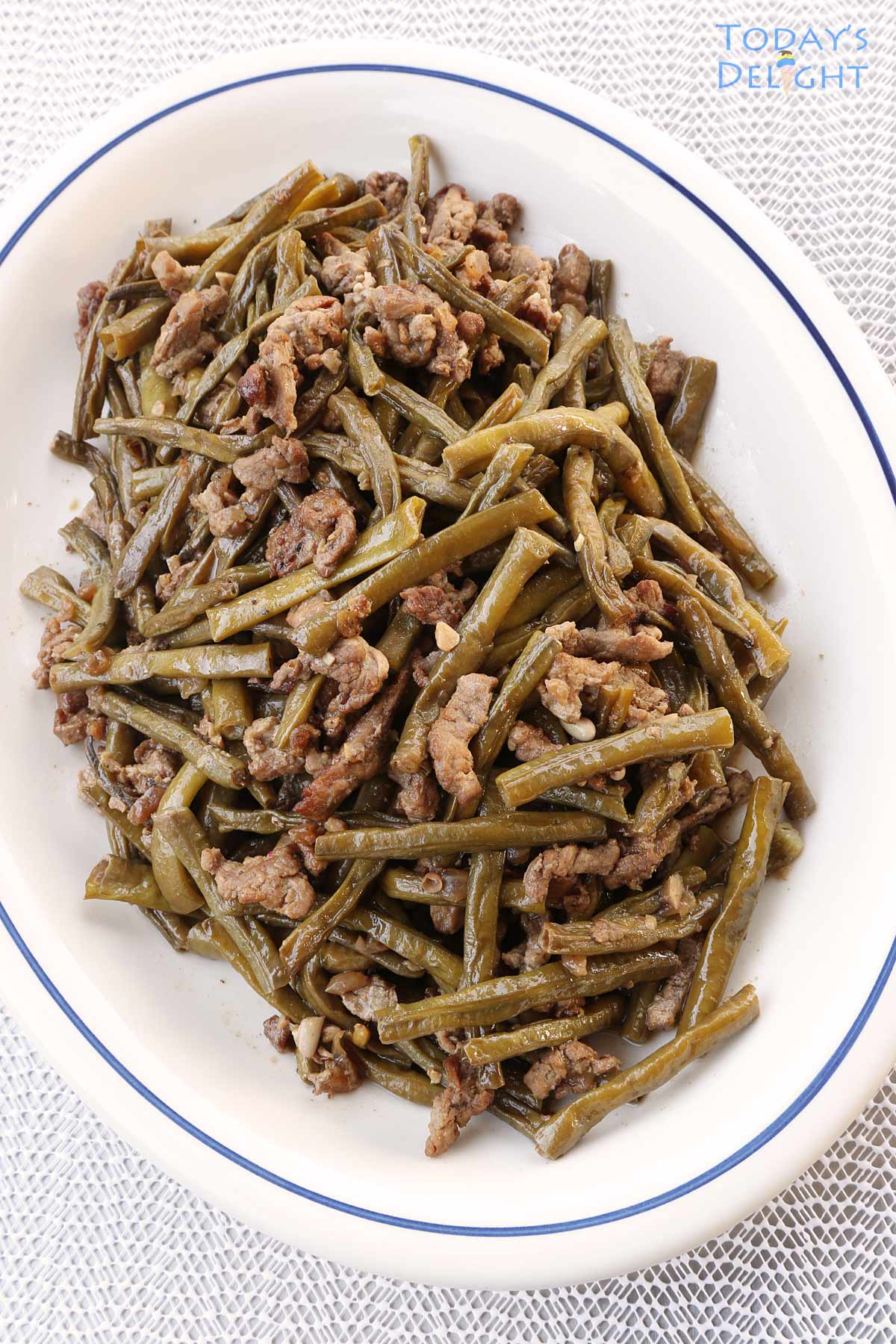 Cooked cut string beans with pork in a platter.