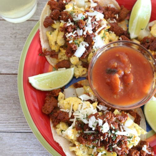 Breakfast tacos with chorizo, eggs and potatoes with limes wedges and salsa.