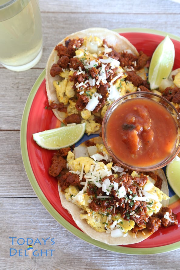Breakfast tacos with chorizo, eggs and potatoes with limes wedges and salsa.