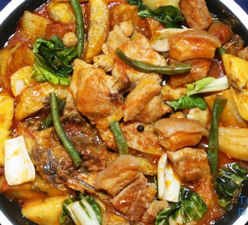 Pork and Chicken Pochero in a pan is a Filipino stew with pork, chicken, vegetables and plantain banana in tomato sauce.
