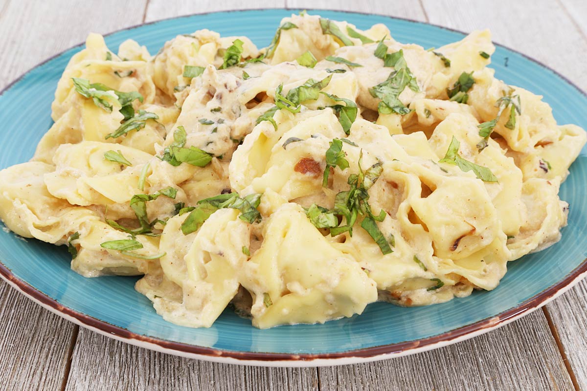 Cheese tortellini with basil cream sauce on a plate.