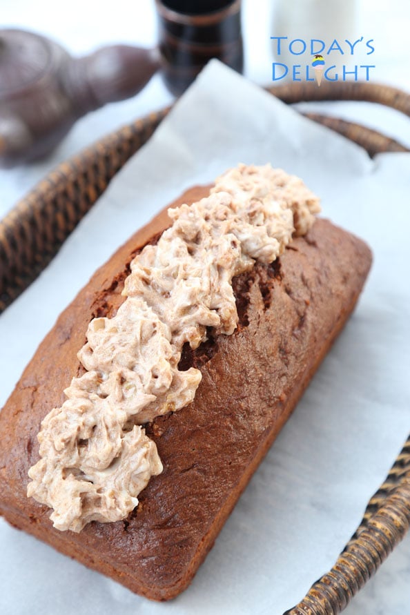 Pumpkin spice bread with cream cheese frosting on a wooden tray.