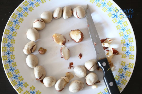 Cooked jackfruit seeds are peeled with a knife on a plate.