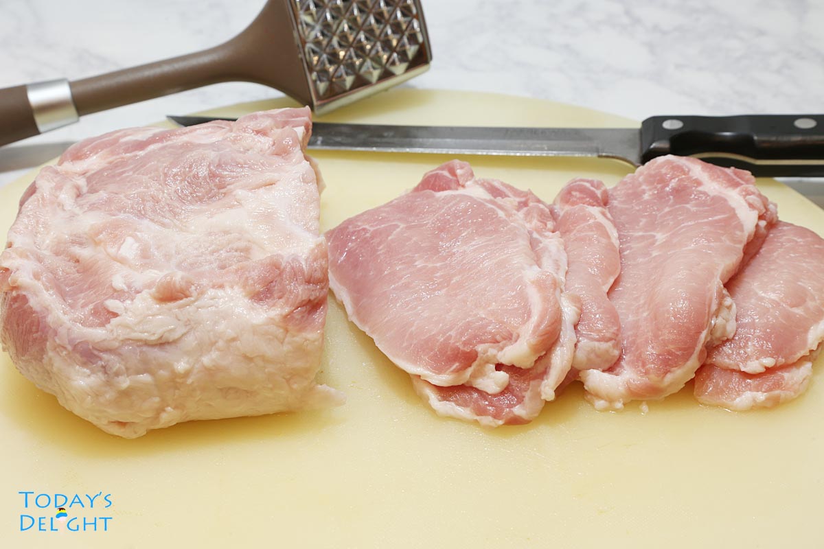 Pork tenderloin sliced into ½ inch thick in a cutting board, a knife and a meat mallet.