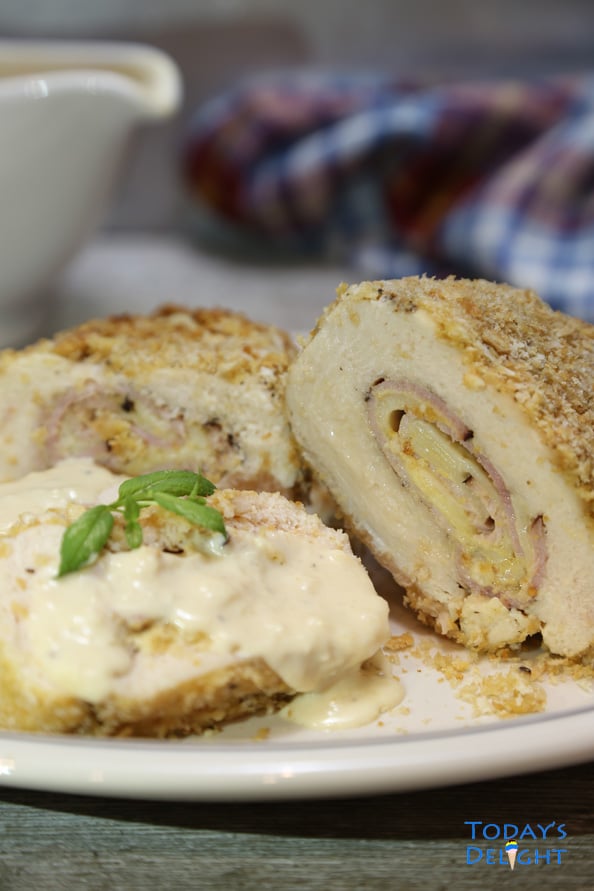 Sliced baked chicken cordon bleu on a platter and a saucer on the side.