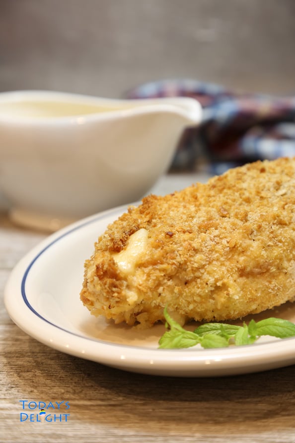 Chicken cordon bleu on a plate and creamy mustard sauce in a saucer.