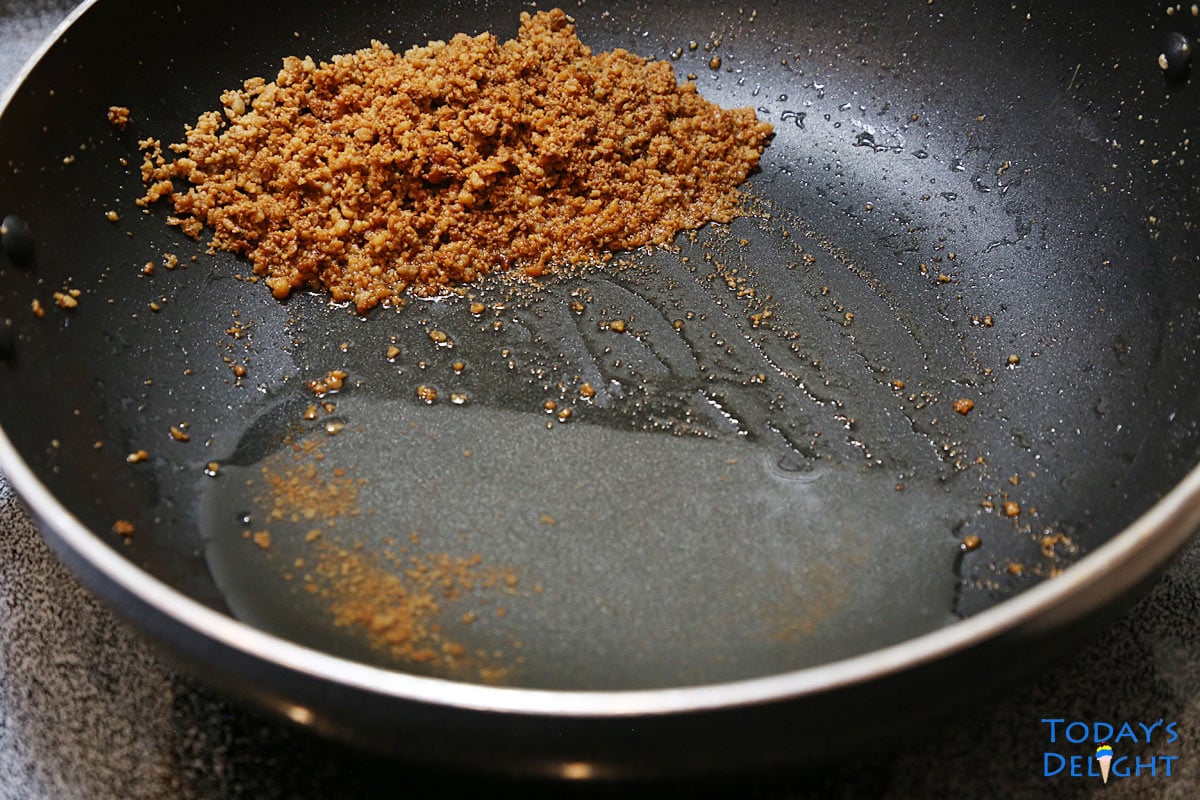 Skillet is tilted and latik (toasted coconut curds) is pushed to the top so coconut oil can flow downward.