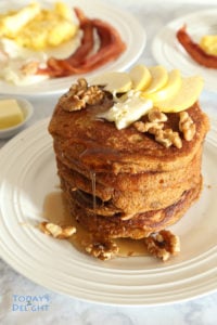 Layers of krusteaz pumpkin spice pancake with walnuts, apple slices and pancake syrup.