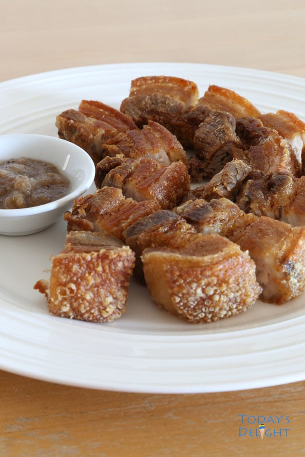 Super crispy sliced lechon kawali (seasoned pork belly) on a plate with Mang Thomas sauce.