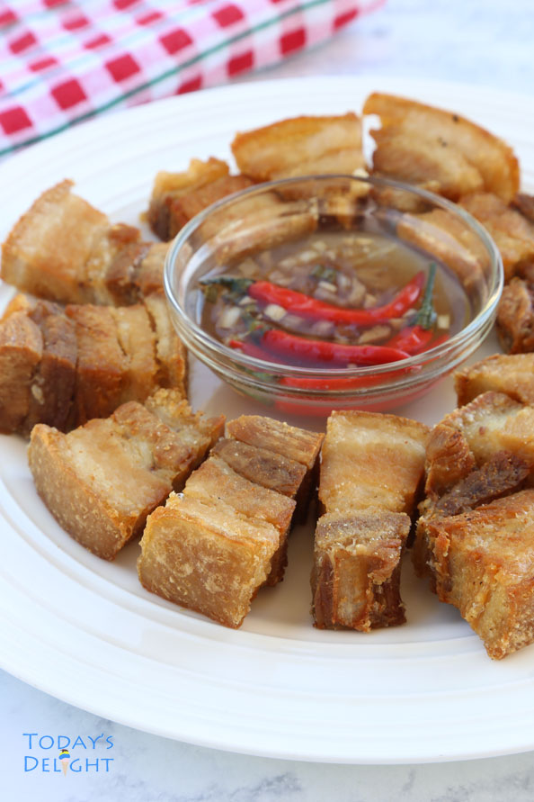 Spicy vinegar dip surrounded by sliced cripsy lechon kawali - fried pork belly in a platter.