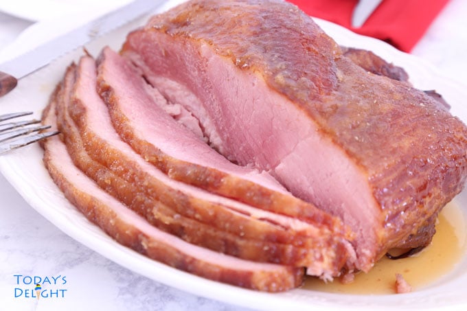 Pineapple carver ham with brown sugar glazing on a platter with a serving fork.