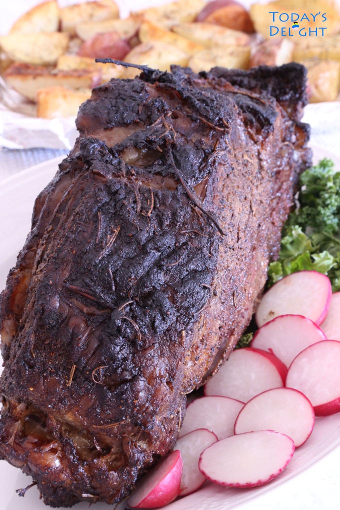 Grilled rib eye roast garnished with kale and sliced radish on a platter.