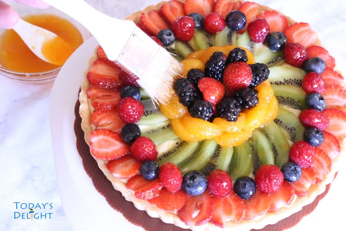 Fruit tart covered with different fruits is brushed with apricot glaze.