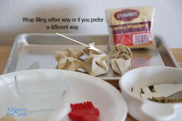 Wonton wrapped in 2 ways on a tray. Wrapper, wonton meat, plate and utensils on the table.