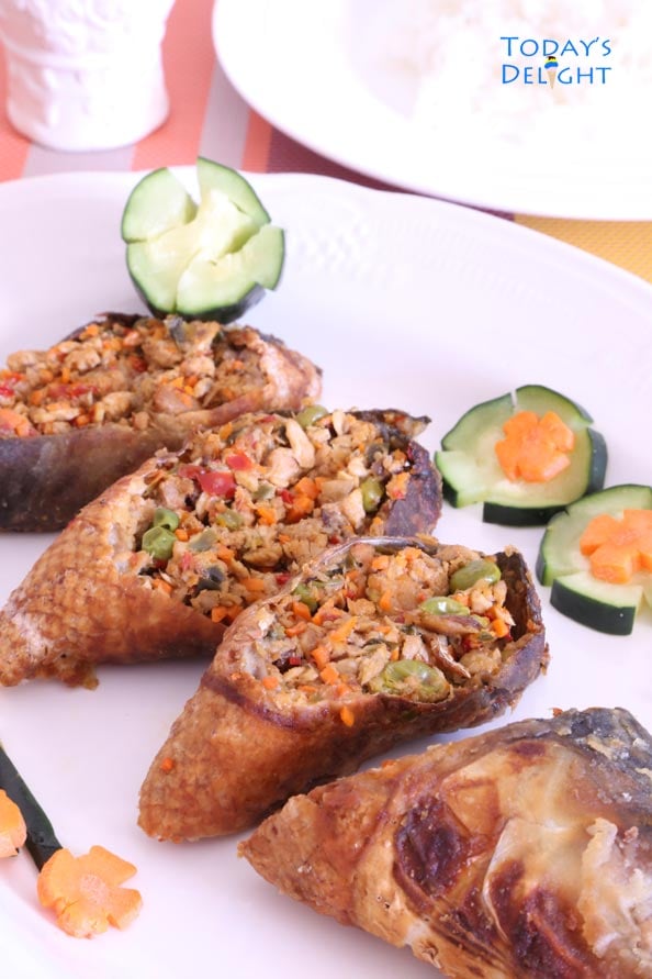 Four slices of Filipino rellenong bangus (stuffed milkfish) with decorative cucumber and carrots on a platter.