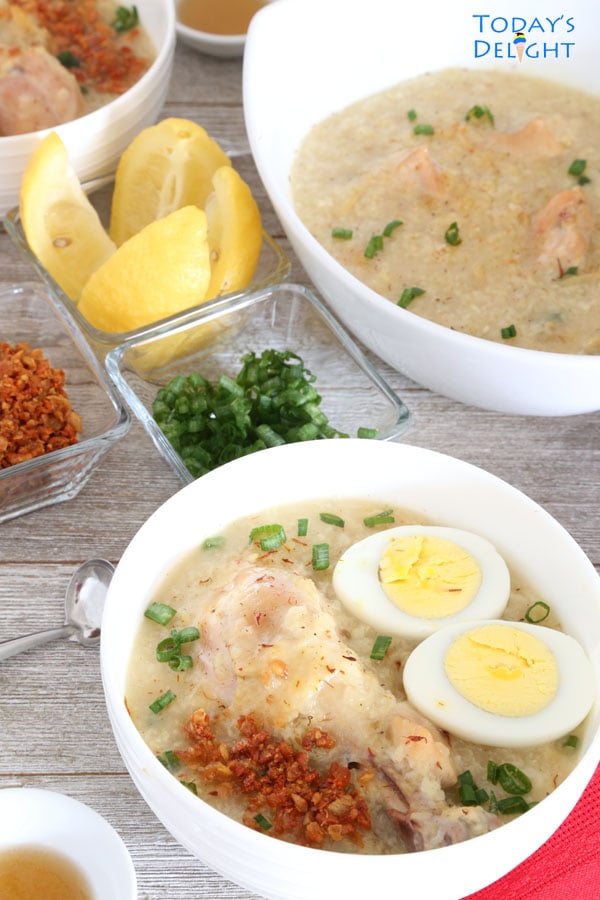 A bowl of Arroz Caldo porridge made with chicken, hard-boiled egg sprinkled with toasted garlic and green onion seasoned with lemon and fish sauce.
