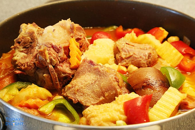 Oxtail, tripe, smoke pork hock and vegetables in a skillet.