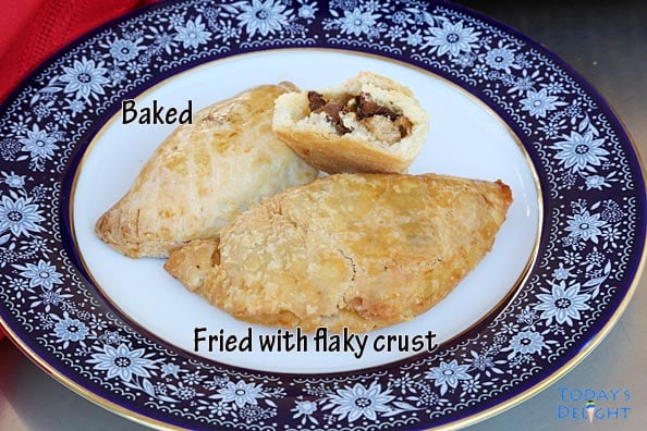 Image showing a baked and fried Filipino empanada on a decorative plate.