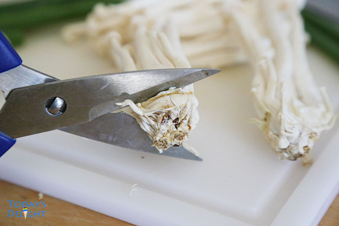 Trimming enoki mushroom roots before cooking