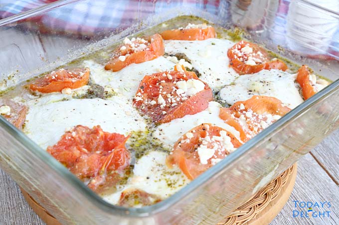 Pesto chicken bake with Tomato Mozzarella and Feta Cheese in a pyrex pan.