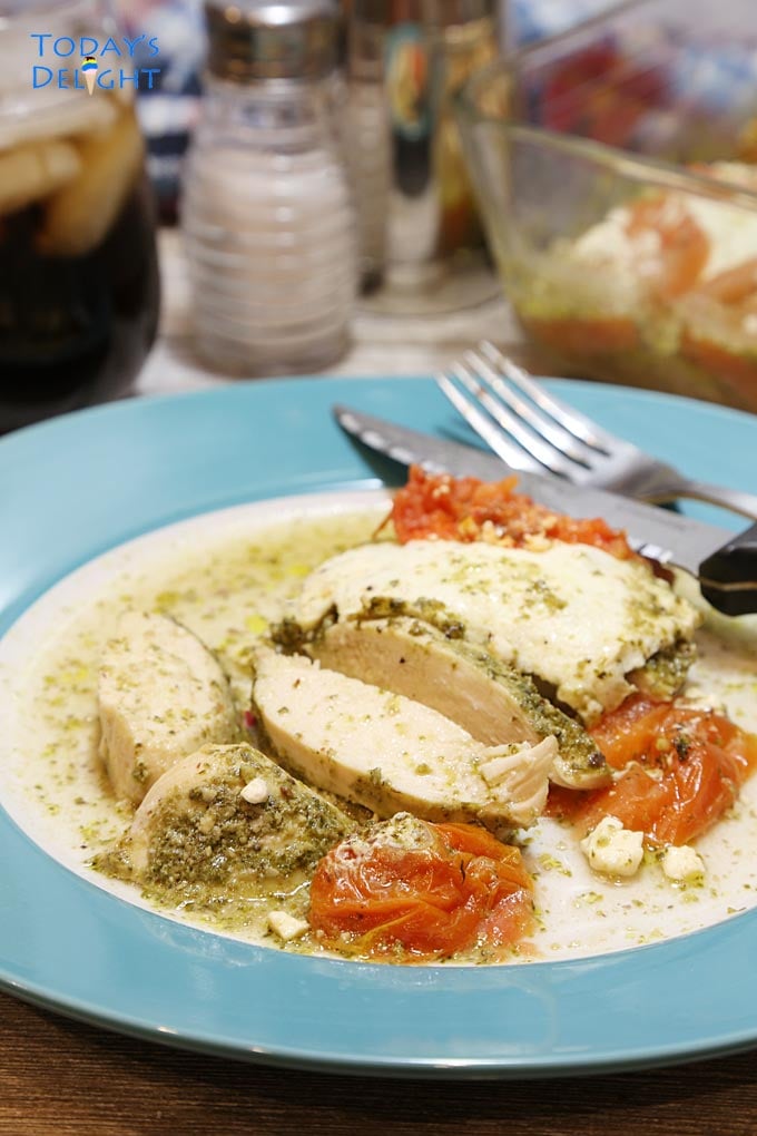 Tender, juicy baked chicken pesto sliced with tomatoes on a plate.