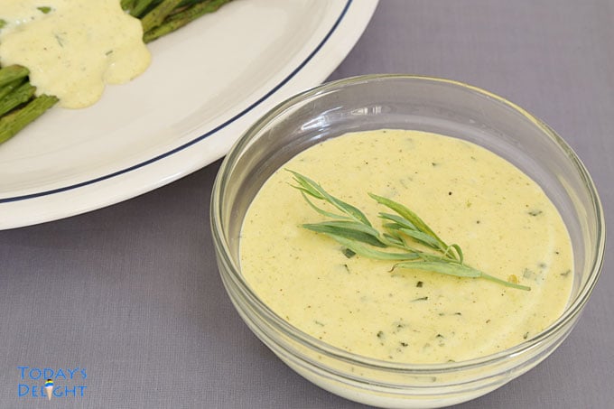 Bearnaise Sauce garnished with tarragon and a side of asparagus with sauce.