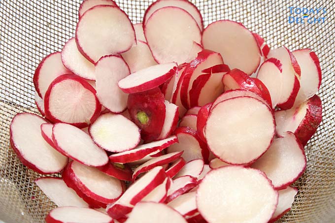 Sliced red radish in a colander.