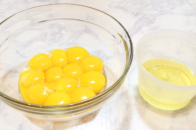 A dozen of egg yolks separated from egg whites in two separate bowls.