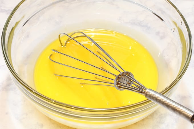 Egg yolks lightly beaten with a whisk in a bowl.