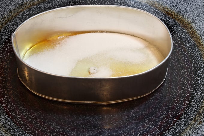 White sugar in flan pan to caramelize on stove top.