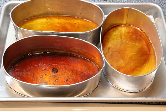 3 leche flan pans with caramelized sugar on a tray.