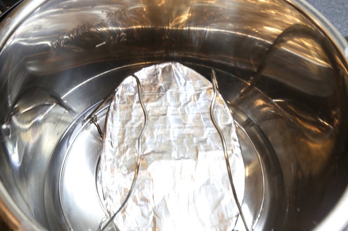 Leche flan covered with a foil on top of a trivet in an instant pot.