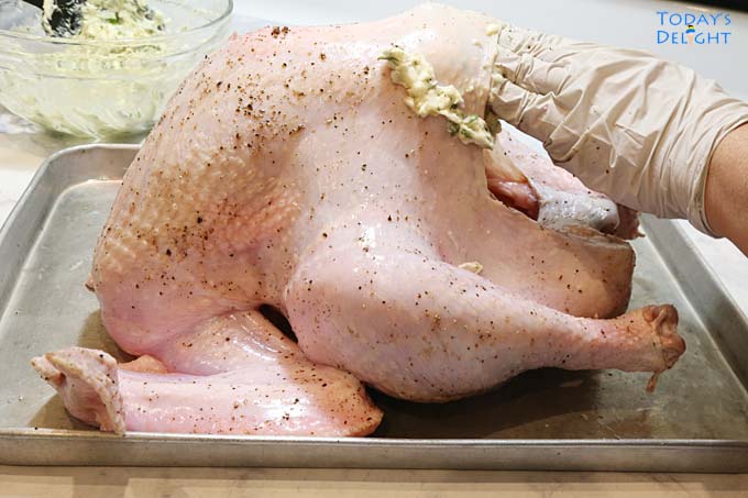 Spreading seasoning under turkey skin using finger and hand.