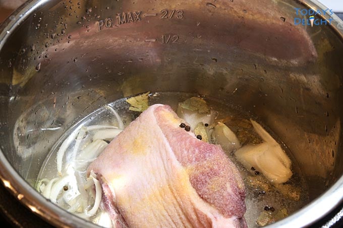 Pork hock with water, onion, peppercorn and seasonings in an instant pot.