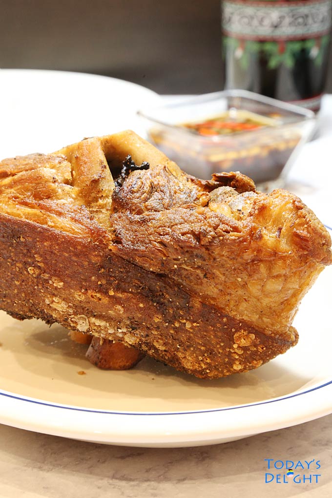 Crispy pork leg with vinegar dip and a glass of soda.