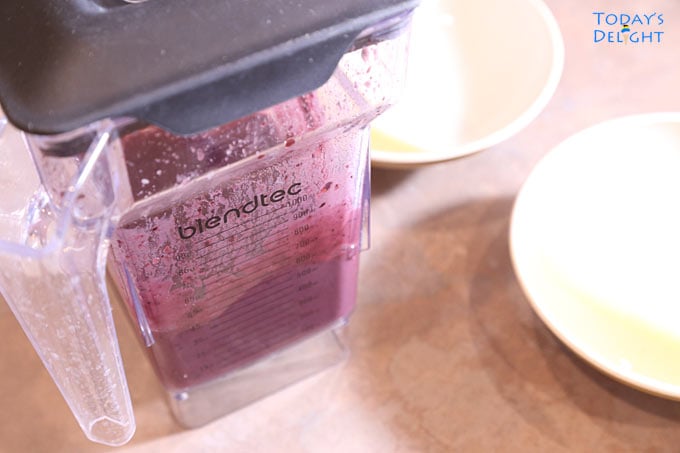 A blender with acai puree and two empty bowls.
