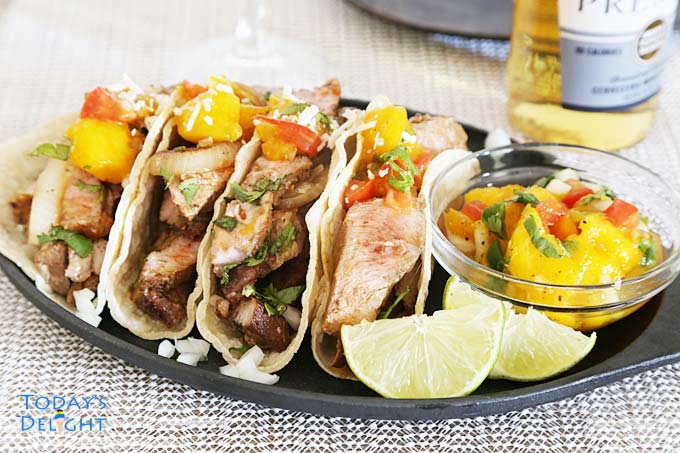Pork tacos with wedges of lime & mango salsa.