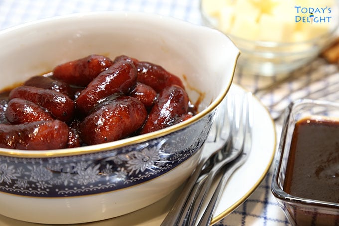 Barbecue little smokies in bowl with small serving forks, bbq sauce and cheese on the side.
