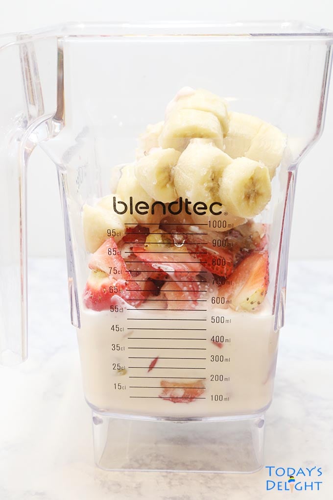 Banana, strawberries, Greek yogurt and milk in the blender to make smoothie.