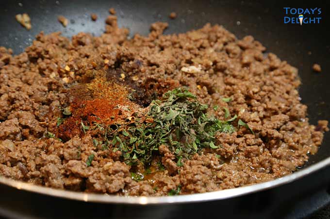 Ground beef with seasonings in skillet.