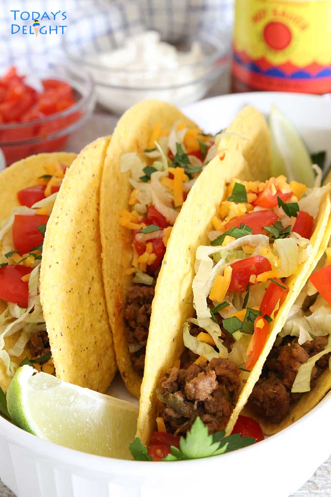 Tacos topped with lettuce, tomatoes and cheese.